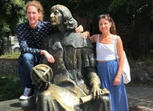 pomnik Mikołaja Kopernika, obok niego stoi dziewczyna i chłopak